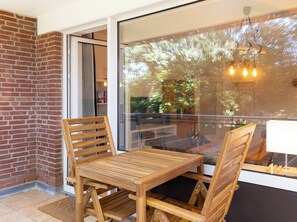 Ein Holztisch und -stühle in einem Raum mit einer Glastür, die auf einen Balkon führt.