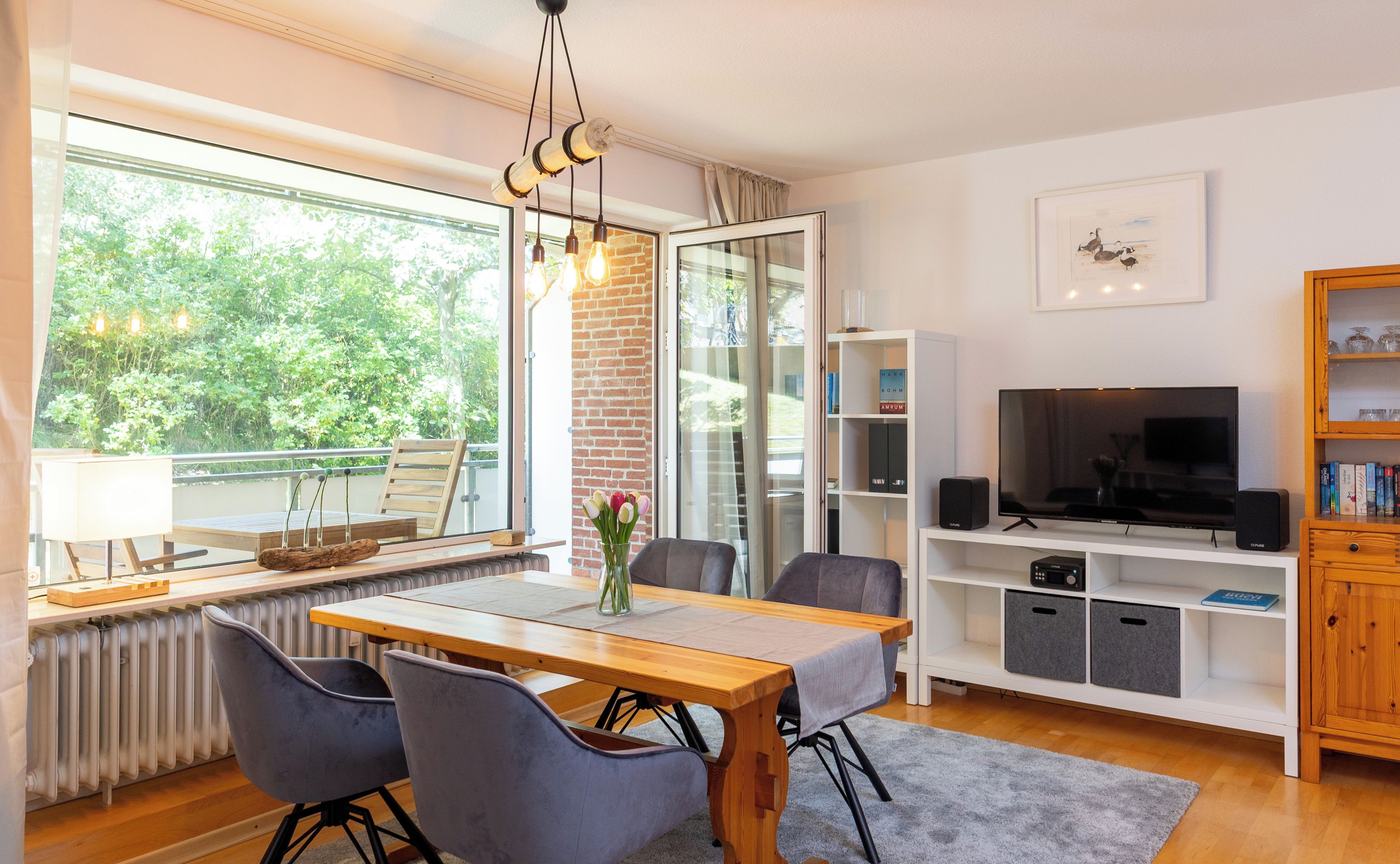 Una sala de estar moderna con comedor, televisor y estantería.
