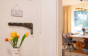 En vägg med en skylt där det står ”Ich willkommen” och en träskylt med texten ”AMRUM”. På väggen finns också en vas med tulpaner och en glad gubbe.