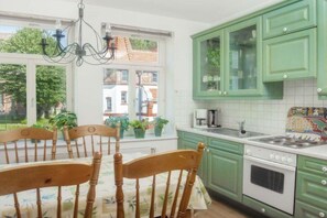A kitchen with green cabinets, a white stove, and a dining table with chairs. - in the heart of the old town (Heiligenhafen)
