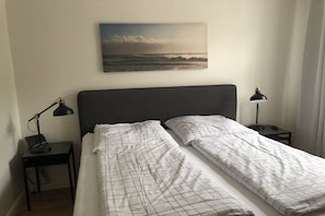 Ett sovrum med en säng, två sängbord och en tavla som hänger på väggen.