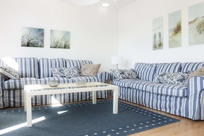 A living room with two striped sofas, a white coffee table, and a blue rug. - in the heart of the old town (Heiligenhafen)