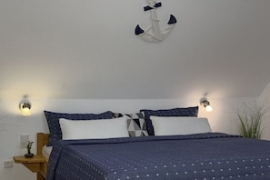 Ein Schlafzimmer mit einem Bett, zwei Wandlampen, einem Nachttisch aus Holz und einer Hängelampe.