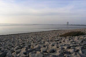 Ein felsiger Strand mit einem Gebäude in der Ferne.