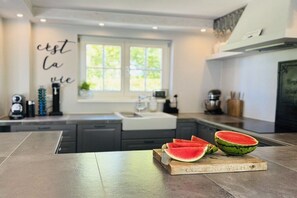 A modern kitchen with a large window, a countertop with watermelon slices, and a decorative wall sign. - Holiday home with 2 bedrooms (Steinberg)