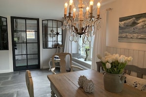 A dining area with a wooden table, a chandelier, and a vase of white flowers. - Holiday home with 2 bedrooms (Steinberg)
