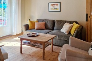 Ein Wohnzimmer mit grauem Sofa, Couchtisch aus Holz und einem gerahmten Bild an der Wand.