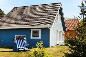 A house with a tiled roof, a blue exterior, a small window, and a blue and white striped chair in the yard. - Holiday home in Prerow with swimming pool (Prerow)