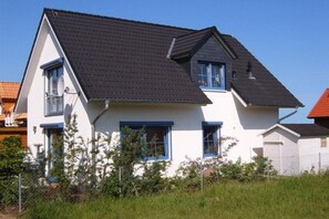 A two-story house with a dark roof, white walls, and blue trim. - Holiday home with 1 bedroom (Insel Poel - OT Kaltenhof)