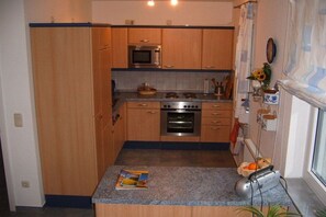 Eine kleine Küche mit Holzausstattung, einer Mikrowelle, einem Backofen und einem Toaster.