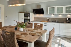 A modern kitchen with white cabinets, a built-in microwave, and a flat-screen TV. - Villa in Sellin with swimming pool (Sellin)
