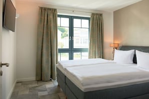 A hotel room with a bed, curtains, a television, and a window with a view.