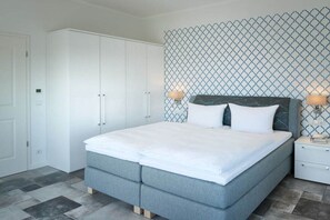 A bedroom with a bed, nightstands, a wardrobe, and a patterned wall. - Villa in Sellin with swimming pool (Sellin)