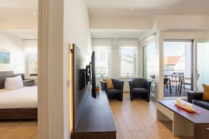 Ein modernes Hotelzimmer mit Bett, Schreibtisch, zwei Stühlen und einem Balkon mit Blick.