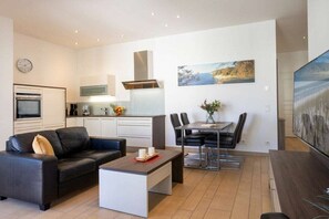Ein modernes Wohnzimmer mit einer Couch, einem Couchtisch und einem Essbereich mit Stühlen und einem Tisch.