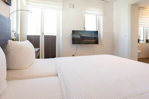 Ein Hotelzimmer mit Bett, einem Bild an der Wand und einem Fenster mit Jalousien.