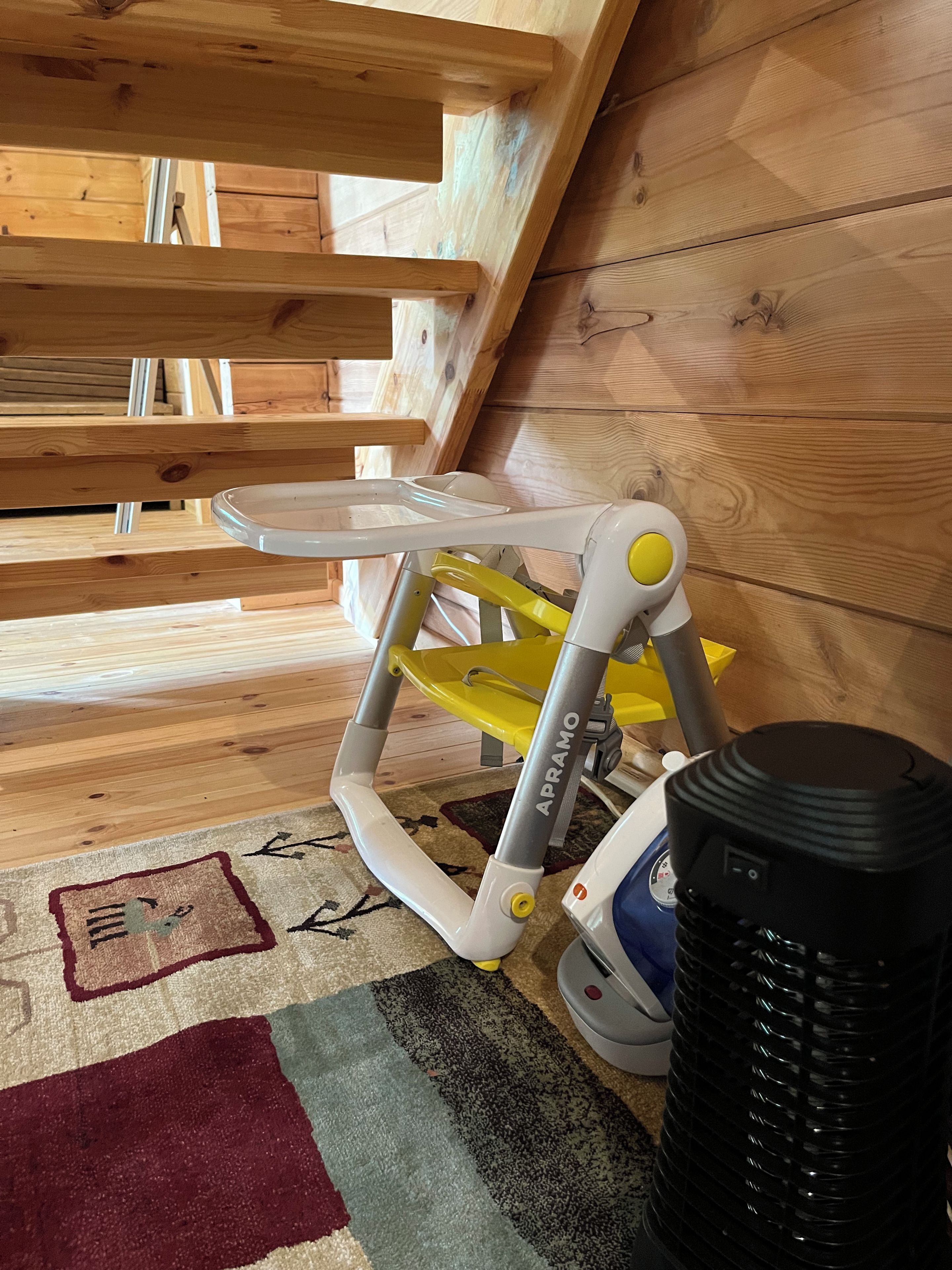 A room with a wooden ceiling, a ceiling fan, a small table, and a rug.
