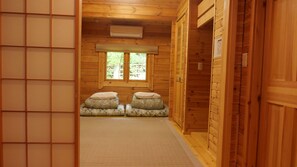 A wooden interior with a window, a wall-mounted air conditioner, and a tiled floor.