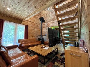 A cozy cabin interior with a sofa, coffee table, and a fireplace.