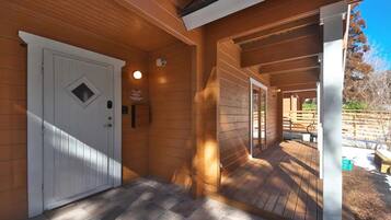A wooden exterior with a white door, a covered porch, and a view of the outdoors.