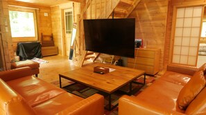 A cozy living room with a large flat-screen TV, leather sofas, and a wooden coffee table.