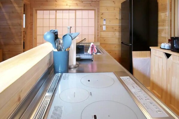 A kitchen with a stainless steel stove, wooden cabinets, and a blue container holding utensils.