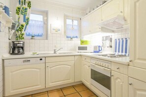 Eine Küche mit weißen Schränken, einem Geschirrspüler, einem Backofen und einer Mikrowelle.