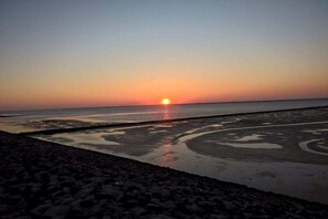 A sunset over a beach with wet sand patterns. - "Hygge" - a thatched-roof house (Nordstrand)