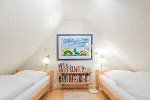A small, cozy room with two wooden beds, a bookshelf with books, and a framed painting on the wall. - "Hygge" - a thatched-roof house (Nordstrand)
