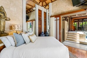 A spacious bedroom with a large bed, a statue, and traditional decor. - Far Pavilions - An Intimate Bali-style Haven (Port Douglas)