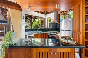 A modern kitchen with a central island, stainless steel appliances, and wooden cabinetry. - Far Pavilions - An Intimate Bali-style Haven (Port Douglas)