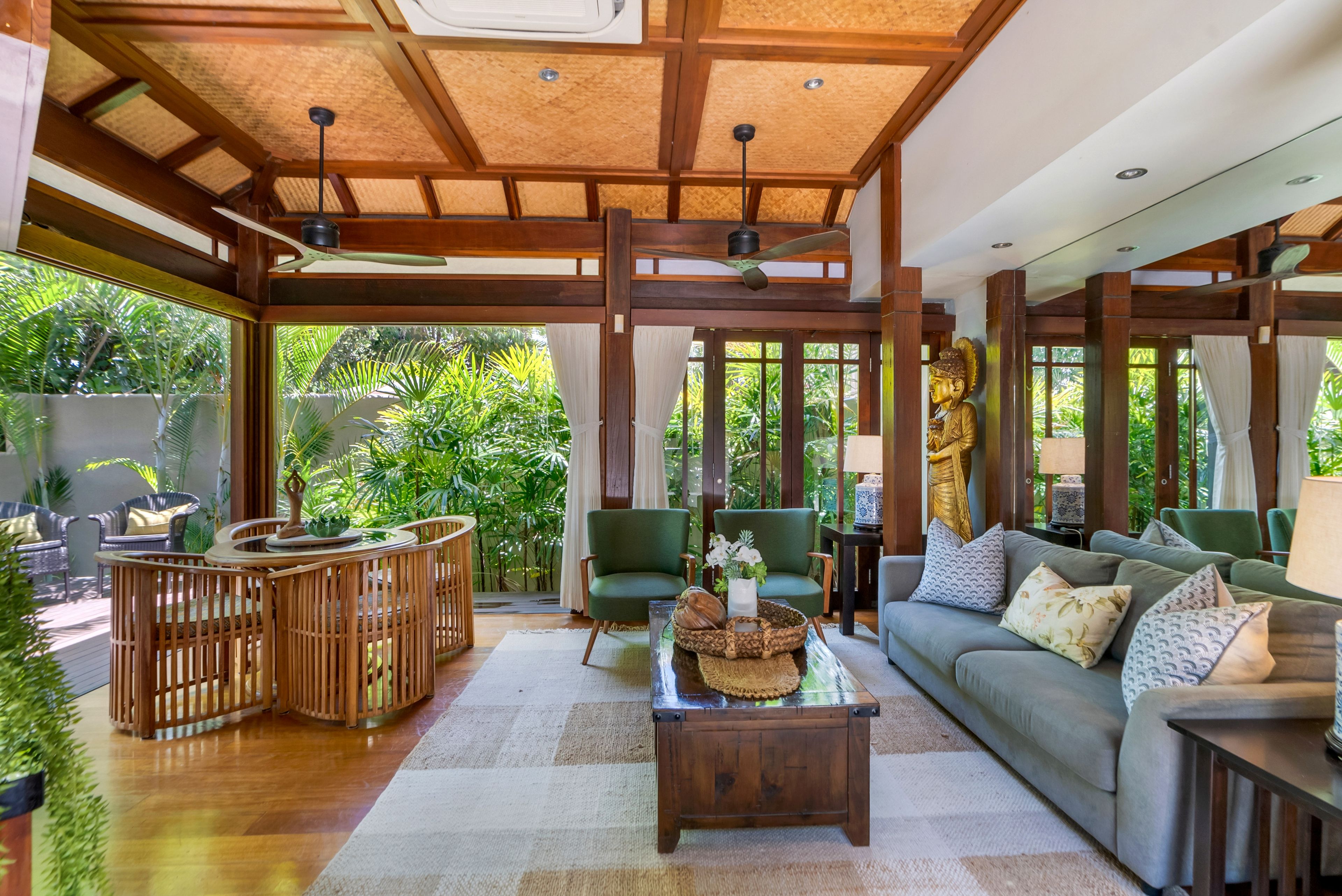 A spacious room with a wooden ceiling, a sofa, a coffee table, and a dining area with chairs and a table.