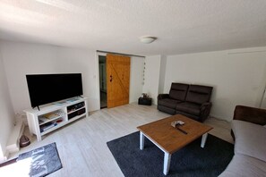 A living room with a flat-screen TV, a brown sofa, a wooden coffee table, and a white entertainment unit. - Relaxation under a thatched roof (Bordelum\/Sterdebüll)
