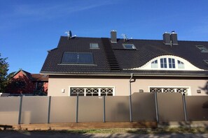 A two-story house with a sloped roof, satellite dishes, and a garage with a gated entrance. - Holiday home with 3 bedrooms (Osteebad Prerow)