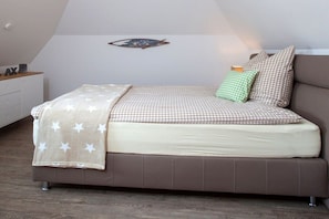 Ein Schlafzimmer mit Bett, Kissen, Wanddekoration und Nachttisch.