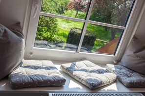 Ein Fensterplatz mit Kissen und Blick auf einen Garten.