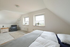 A bedroom with a bed, a chair, a nightstand, a floor lamp, and two windows. - Holiday apartment in Rade with barbecue (Rade)