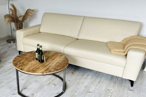 A beige leather sofa with a round wooden coffee table, a blanket, and pampas grass in a room with light wooden flooring. - Holiday apartment in Rade with barbecue (Rade)