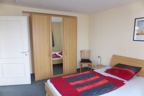 A bedroom with a bed, a wardrobe, a chair, and a bedside table. - Miramare Apt. 24 in 1st row (Kühlungsborn)