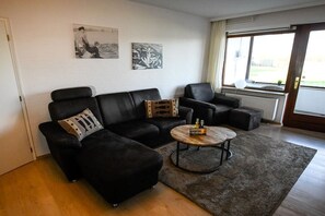 A living room with a black sofa, a round coffee table, and two armchairs. There are two framed pictures on the wall. - Holiday apartment in Rade with barbecue (Rade)