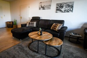 A living room with a sectional sofa, two round coffee tables, a small side table, and a door. - Holiday apartment in Rade with barbecue (Rade)