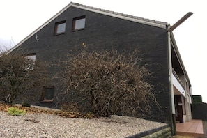 A building with a sloped roof, a small window, and a gravel driveway. - Holiday apartment in Rade with barbecue (Rade)