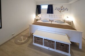 A bedroom with a double bed, bedside tables, a nightstand, a window with curtains, a wall decoration, and a small storage unit under the bed. - Holiday apartment in Rade with barbecue (Rade)