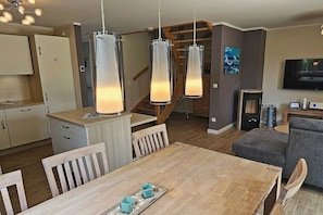 Eine moderne Küche mit Essbereich, Holzmöbeln und einer Treppe, die zu einer weiteren Ebene führt.