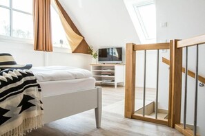 A bedroom with a bed, a TV, a desk, and a staircase. - Holiday apartment with 1 bedroom (Zingst)