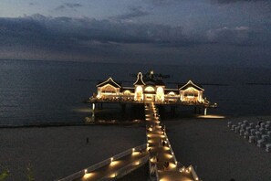 A waterfront hotel with a long pier leading to the building, featuring multiple illuminated structures. - Holiday apartment with 2 bedrooms (Ostseebad Sellin)