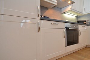 Een keuken met witte kastjes, roestvrijstalen apparatuur en een aanrecht.