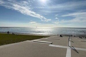 A coastal walkway with a clear view of the sea and a distant ship. - Holiday home with 2 bedrooms (Friedrichskoog)