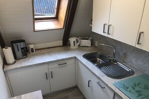 A compact kitchen with a sink, a toaster, a kettle, and a window. - Holiday home with 2 bedrooms (Friedrichskoog)