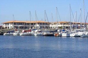 A marina with multiple sailboats docked in front of a row of buildings with red-tiled roofs. - Holiday Dreams by the Sea 5.3 (Kühlungsborn East)